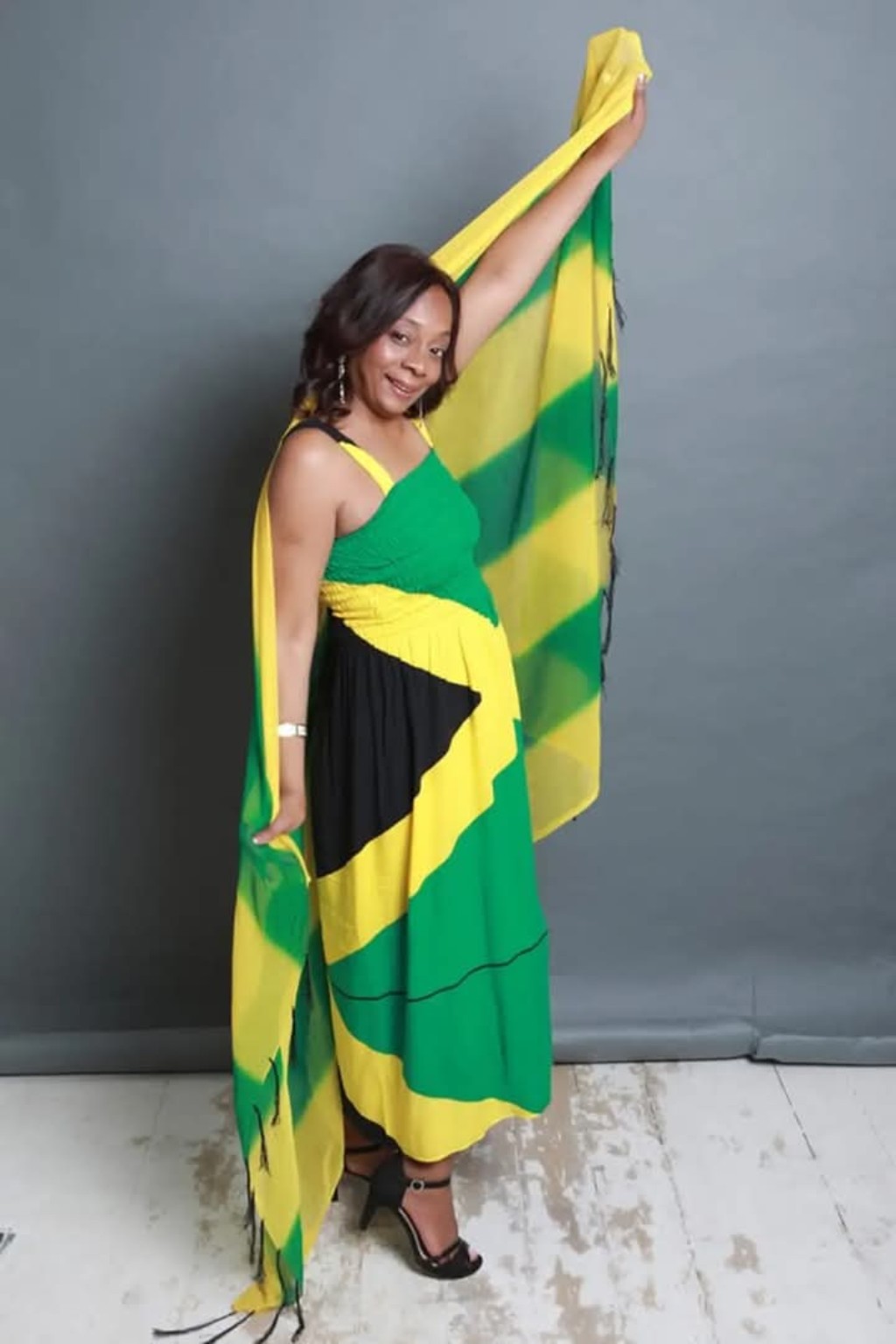Diane standing in a flowing green, gold and black Jamaican outfit